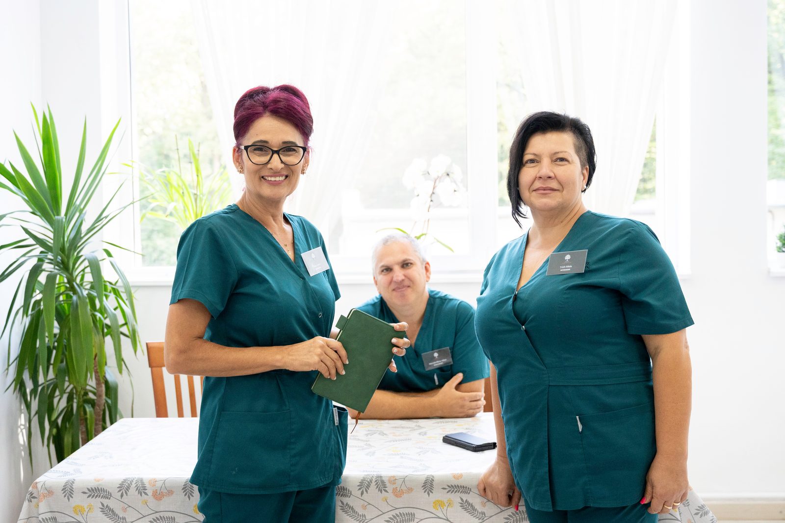 Două asistente medicale alături de un pacient, în salon